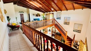 A spacious interior with a wooden staircase, a balcony, and a view of the outdoor area. - Le Domaine du Val de l'Orge (Vieux-Habitants)