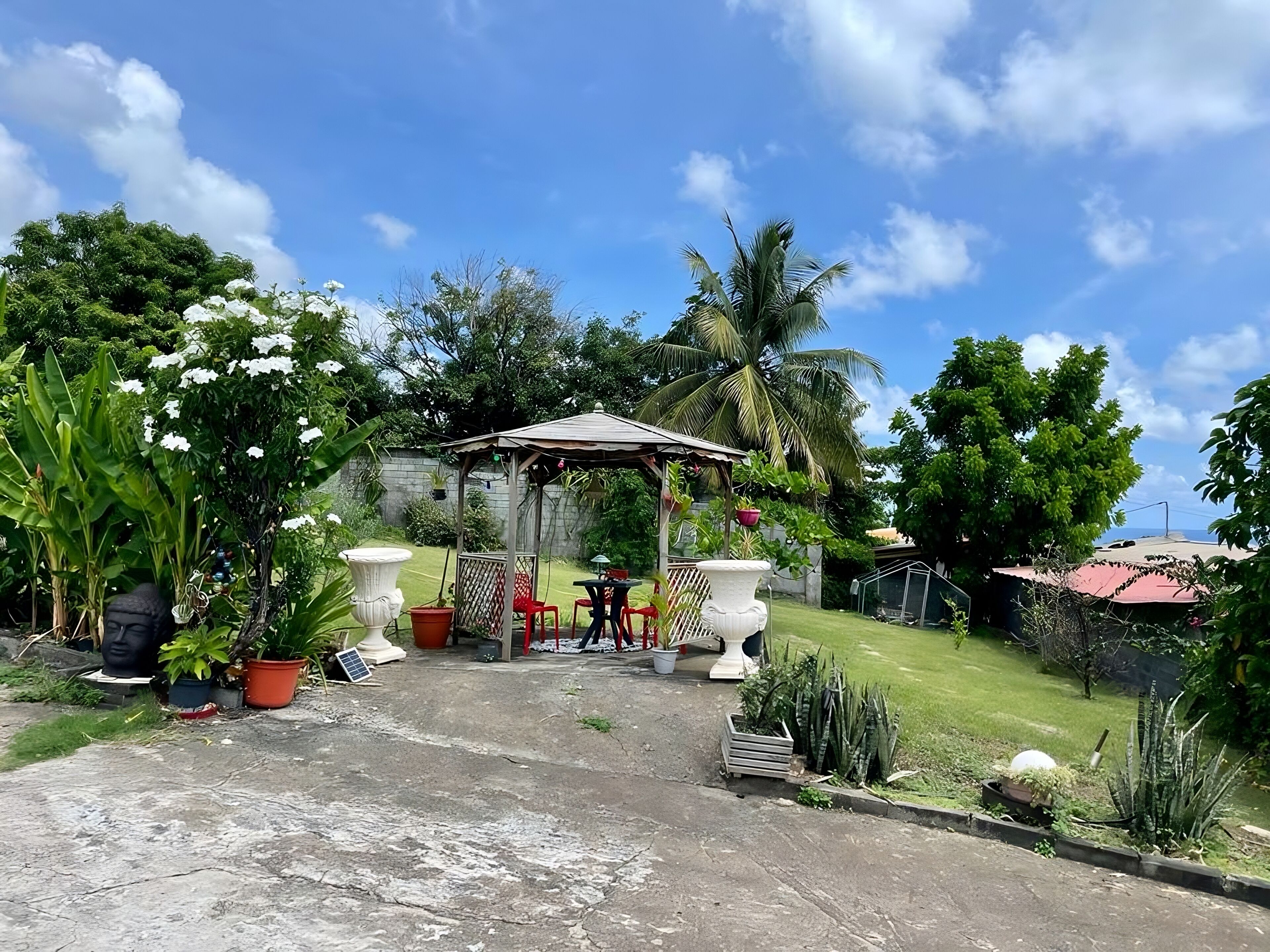 A garden with a gazebo, potted plants, and a lawn.