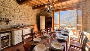 Cocina de piedra rústica con comedor listo para una comida, con un amplio ventanal que ofrece vistas al exterior.