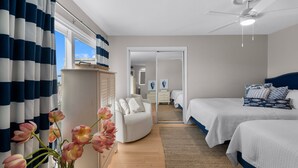 A bedroom with two beds, a ceiling fan, a window with curtains, and a view of the sky. - Boardwalk A4 | Pool, Beach Access | New Renovations! (Pensacola Beach)