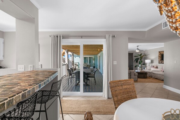 A modern kitchen with a tiled backsplash, a dining area with a wooden table and chairs, and a living room with a sofa and a coffee table.