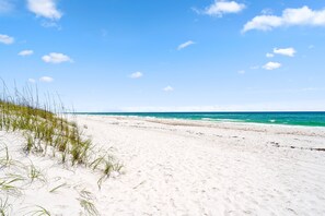 A sandy beach with clear blue skies and ocean waves. - Island Beach Bungalow | Dog Friendly | Seasonal Beach Svc Included | My Beach Getaways (Pensacola Beach)