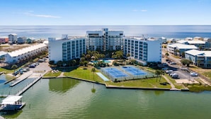 Ein modernes Hotel mit mehreren Etagen, einem Schwimmbad, Tennisplätzen und einem Yachthafen.