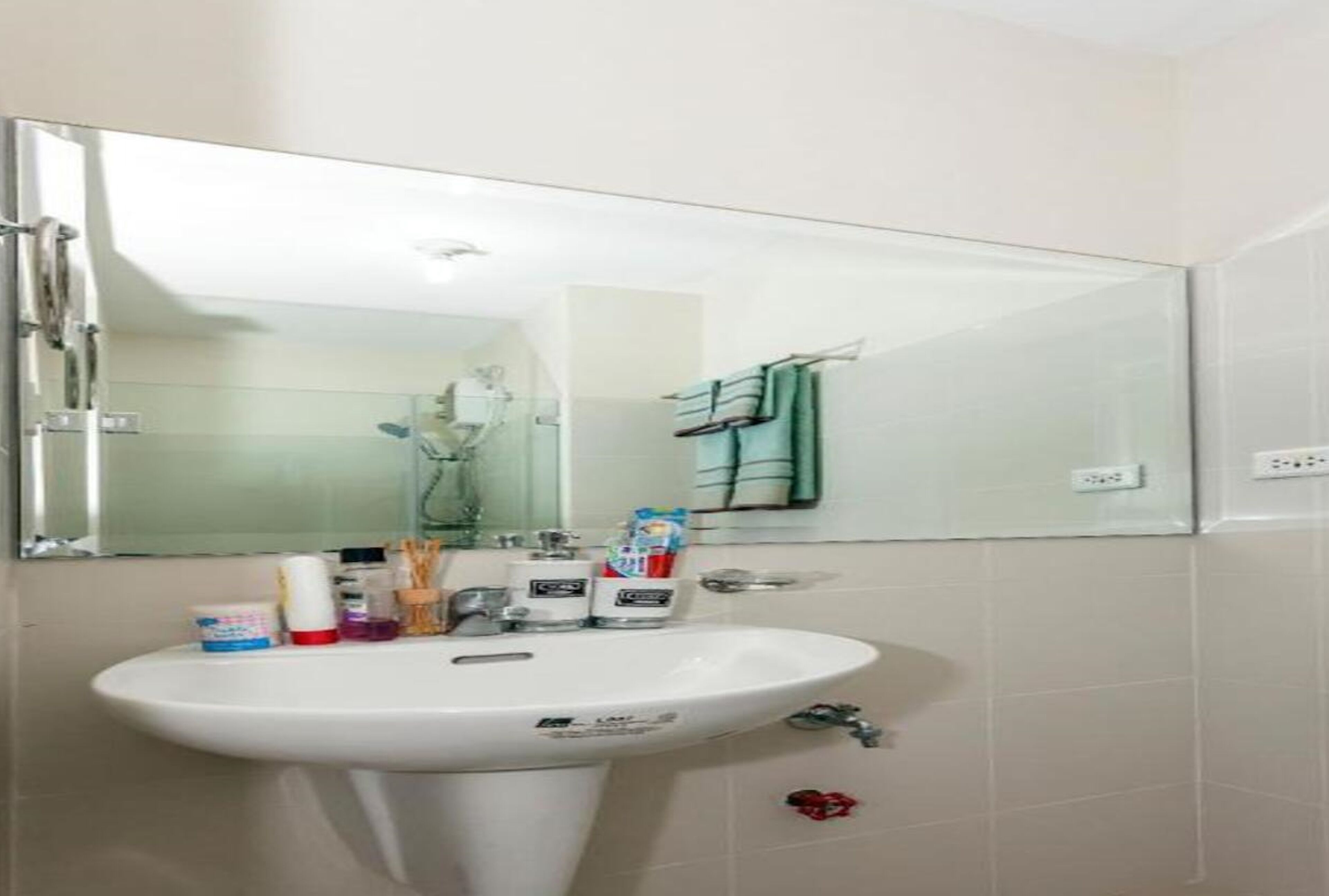 Casa de banho com lavatório branco, espelho e porta-toalhas.