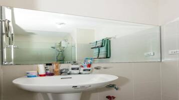Casa de banho com lavatório branco, espelho e porta-toalhas.