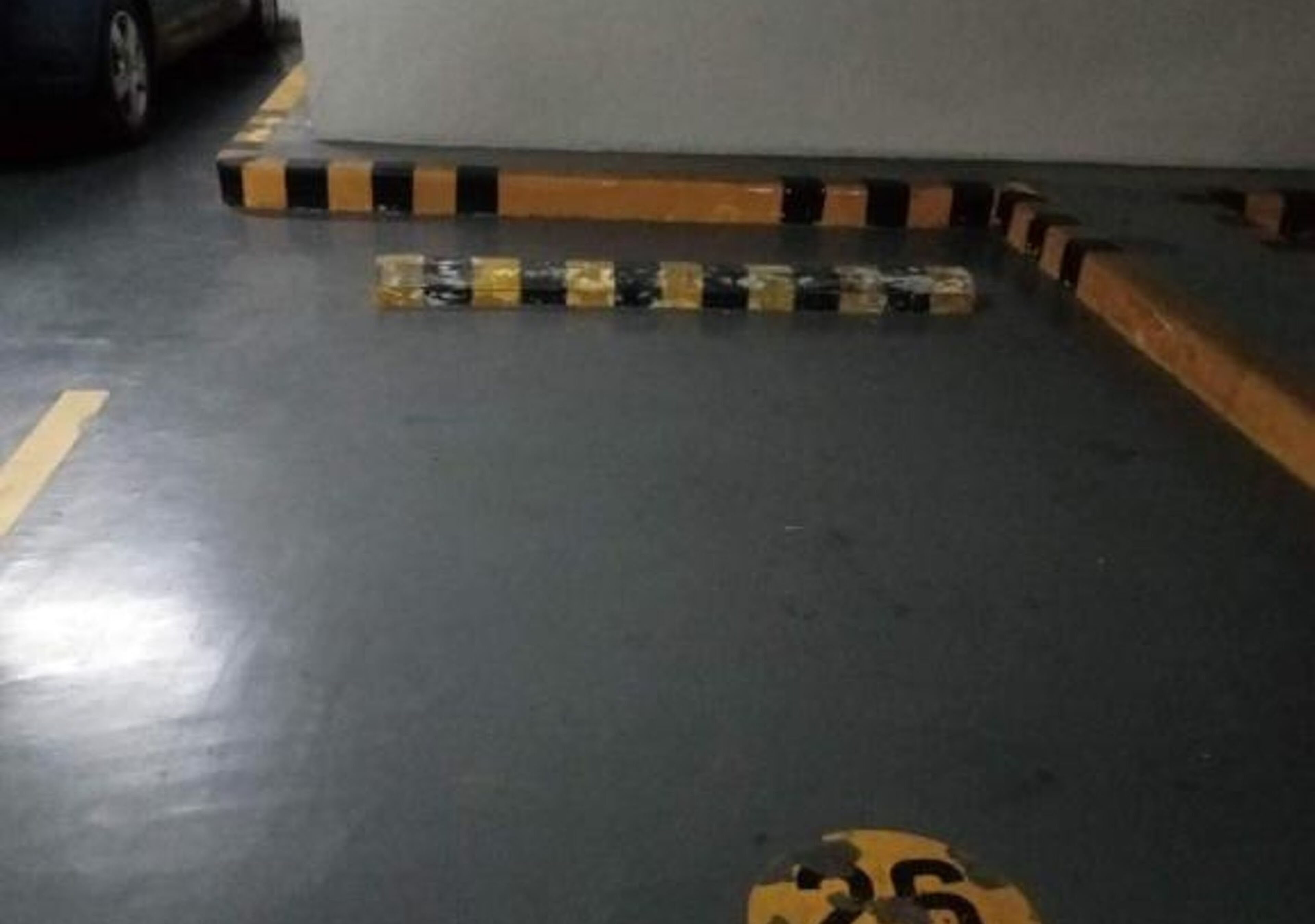 A parking area with marked parking spaces and a yellow line indicating a no-parking zone.