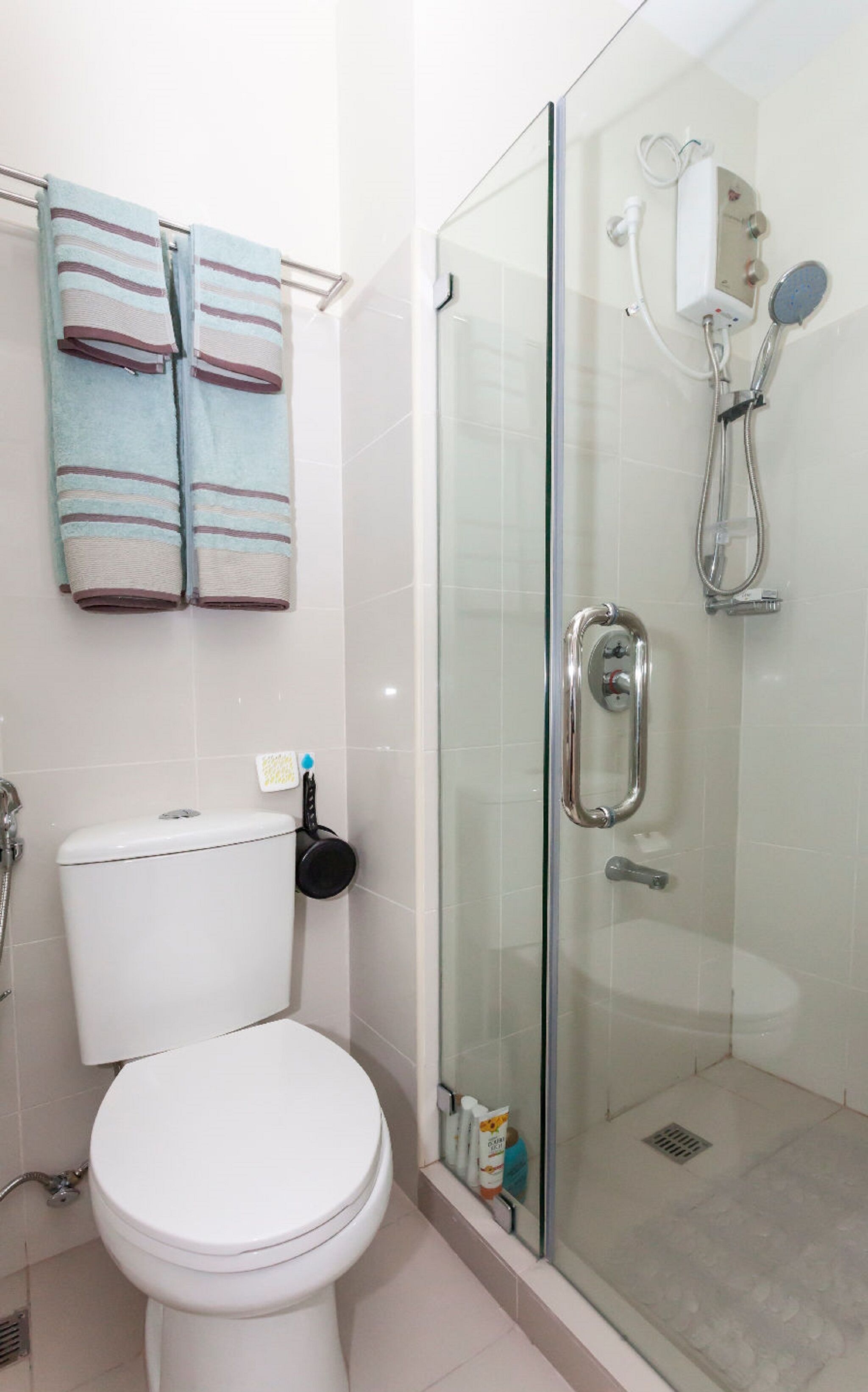 A bathroom with a toilet, a glass shower enclosure, and a towel rack with striped towels.