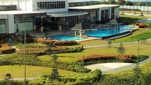 A modern building with a swimming pool, landscaped gardens, and a clear view of the surrounding area. - Blowing In The Wind Tagaytay (Tagaytay)