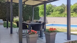 An outdoor patio with a covered dining area, a pool, and potted plants. - Stunning home in Labin (Labin)