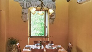 A dining area with a stone-framed window, wooden ceiling beams, and a table set for four with chairs. - Stunning home in Labin (Labin)