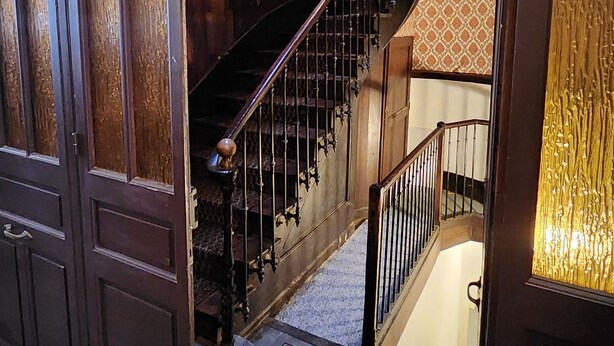 Un magnifique escalier, agrémenté de rampes décoratives et d’un papier peint à motifs, menant à l’étage supérieur.
