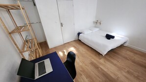 Une pièce comprenant un lit, un bureau avec un ordinateur portable, une échelle en bois et une armoire blanche.