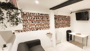 Un salon moderne avec un canapé, un téléviseur fixé au mur et un mur d’accent orné d’un motif en briques.