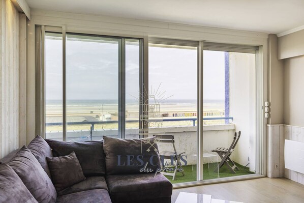 A spacious living room with a large window offering a view of the beach and airport.