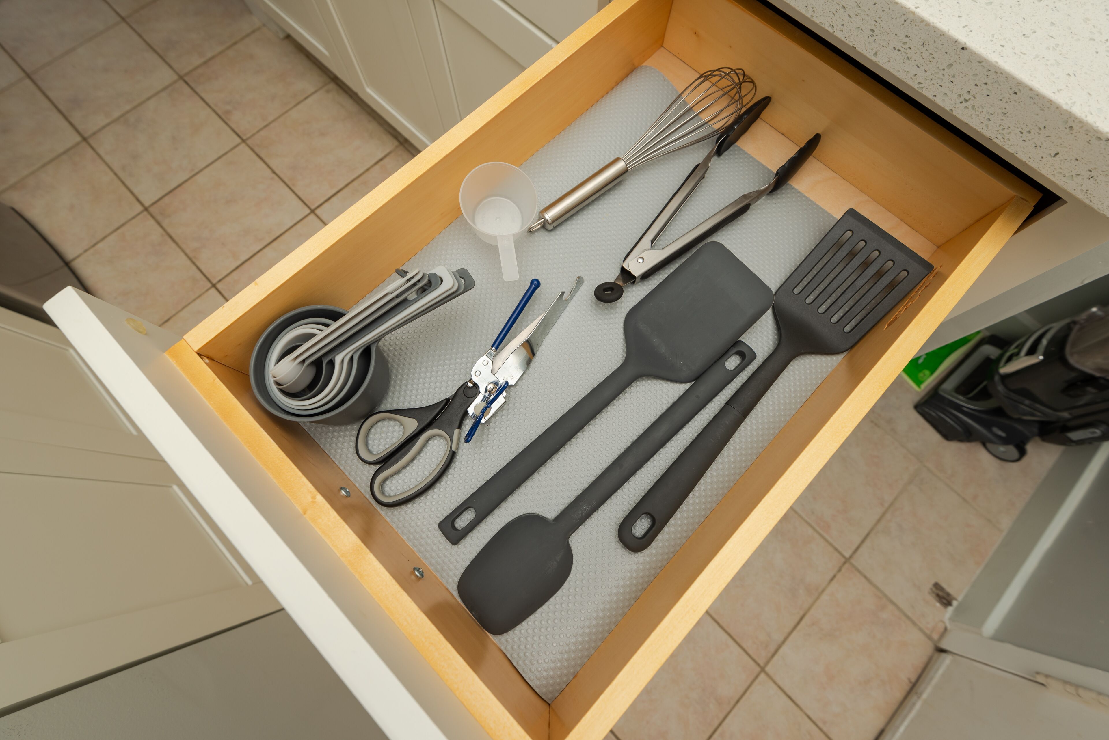 A kitchen drawer with various utensils and tools.