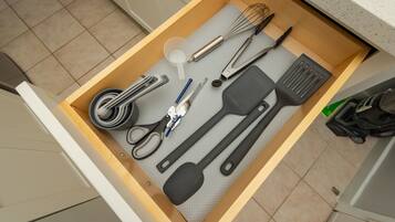 A kitchen drawer with various utensils and tools.