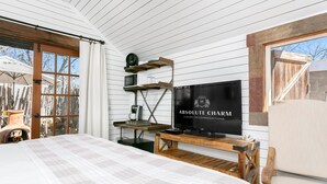 A bedroom with a bed, a television, a coffee maker, and a wooden chair. - Centre St. Cottage | 1/1, King Bed, Mini Kitchen (Fredericksburg)