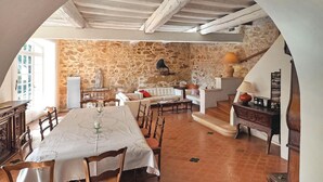 Un comedor con pared de piedra, un sofá blanco y una mesa preparada para dos personas.