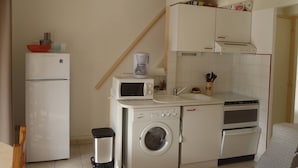 Una cocina compacta con lavadora, cafetera y refrigerador.