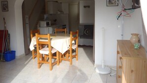 Un comedor con una mesa y sillas, una cocina al fondo y una escalera que lleva a otro nivel.