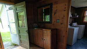 A wooden cabin interior with a wooden door, a mirror, a cabinet, and a washing machine. - Lakefront house with land dock (Conneaut Lake)