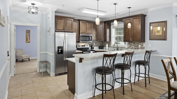 A modern kitchen with a central island, bar stools, and a refrigerator.