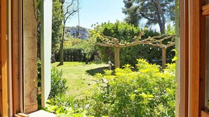 Un jardín con una pérgola, varios arbustos y césped.