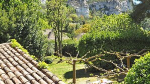 Un patio con techo de tejas, una mesa con sillas y vistas a acantilados rocosos.
