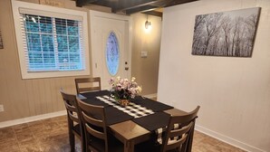 Comedor con mantel a cuadros, cuatro sillas de madera y un jarrón de flores.