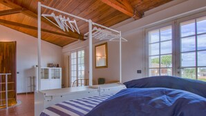 A bedroom with a bed, a hanging clothes rack, a chair, a desk, and large windows. - Le Dune by Interhome (Tirrenia)