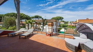 A terrace with outdoor furniture, a pergola, and a view of surrounding buildings and trees. - Le Dune by Interhome (Tirrenia)