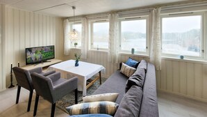 Kodikas olohuone, jossa on televisio, ruokapöytä ja sohva.