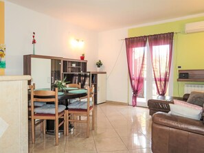 A living room with a dining area, a sofa, and a TV.