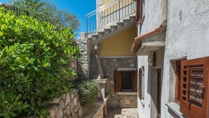 A narrow stone pathway leading to a building with a stone wall and a wooden door. - Victory by Interhome (Labin)