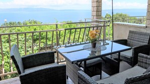 A balcony with wicker furniture, a glass table, and a green umbrella. - Victory by Interhome (Labin)