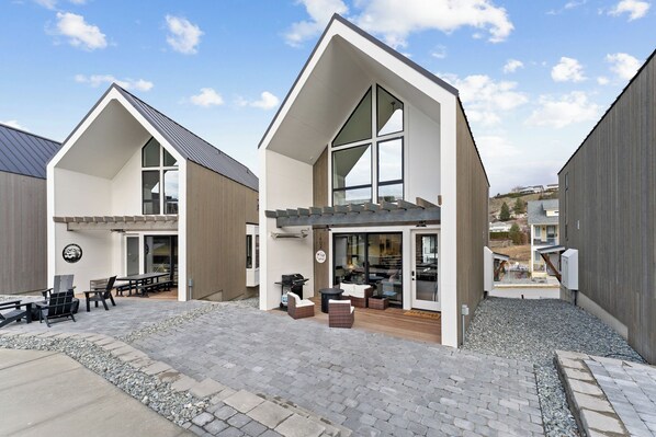 A modern building with a patio area featuring outdoor seating and a grill.