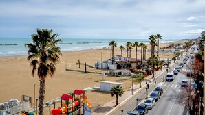Una carretera junto a la playa con palmeras, servicios de playa y vistas al océano.