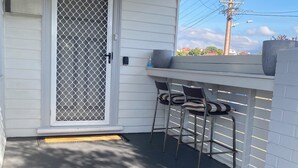 A covered porch with a sliding door, two chairs, a table, and a large planter. - Comfy home within walking distance to beach, restaurants and Blunderstone area. (Bellerive)