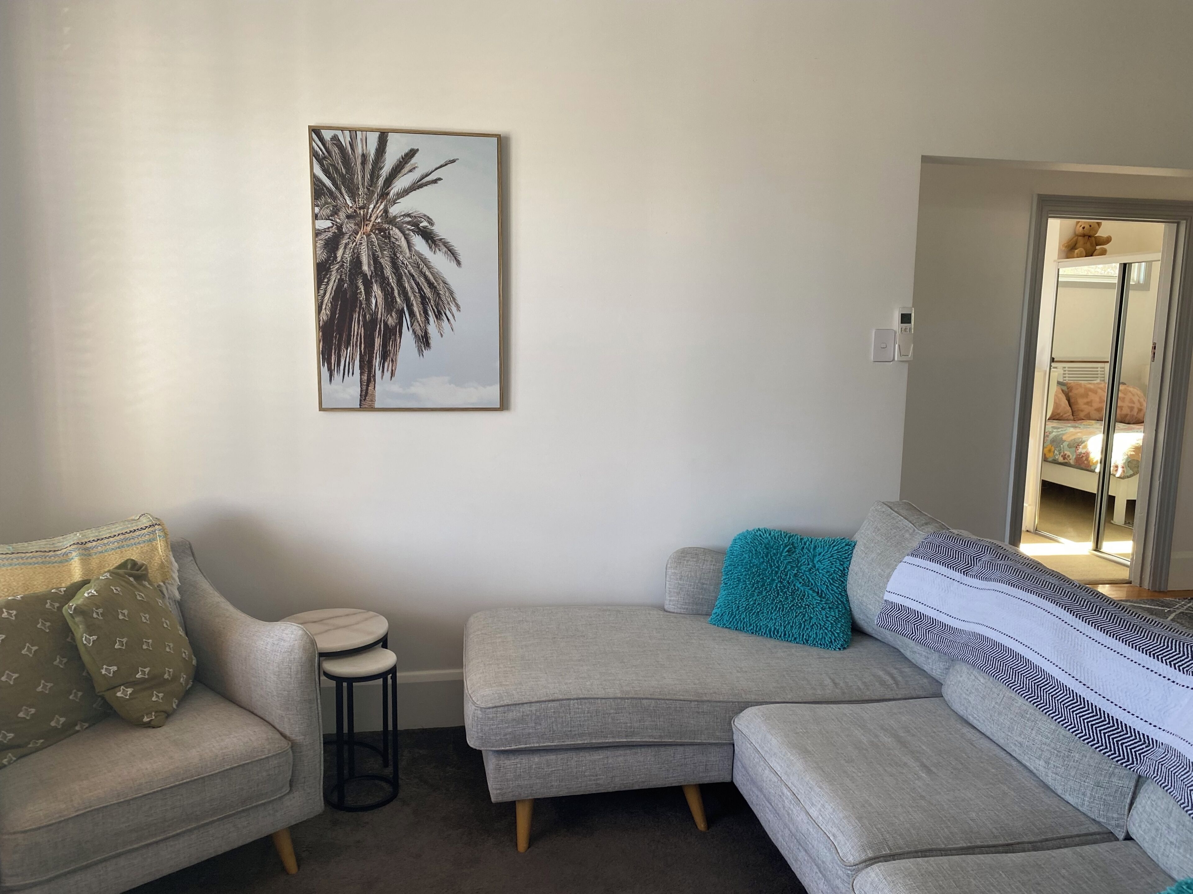 Un salon avec un canapé gris, une petite table ronde et un coussin décoratif de couleur turquoise.