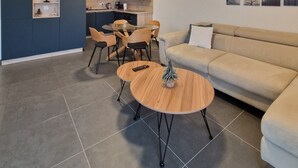 A modern living room with a sofa, a round coffee table, and a dining area with chairs. - The Little Paradise lake view (Annecy)
