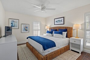A bedroom with a bed, a bedside table, a lamp, a ceiling fan, and framed artwork on the walls. - Water's Edge: Dog Friendly, Canal Front, Dock & Pool & Spa (Anna Maria)