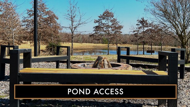 A park area with a wooden bench, a fire pit, and a pond.