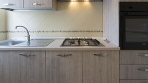 Eine moderne Küche mit Gasherd, Edelstahl-Spüle und Holzschränken.