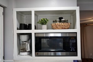 Compact kitchen area with microwave oven and coffee maker.