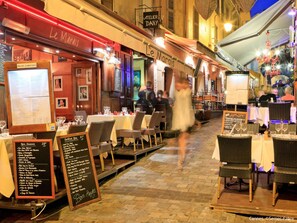 Enjoy a warm and inviting dining experience in our restaurant's outdoor seating area, featuring a brick facade and wooden furniture.