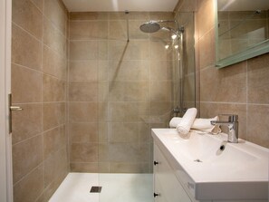 Features a sleek vanity, large mirror, handheld showerhead, and glass shower enclosure.