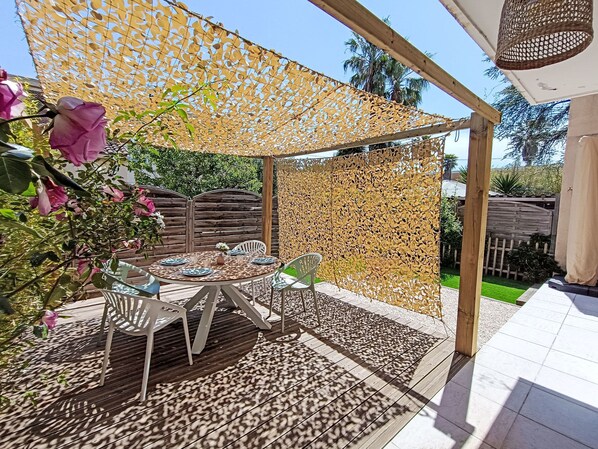 Eine Terrasse im Freien mit einer Holz-Pergola, einem runden Esstisch und einem dekorativen Zaun.