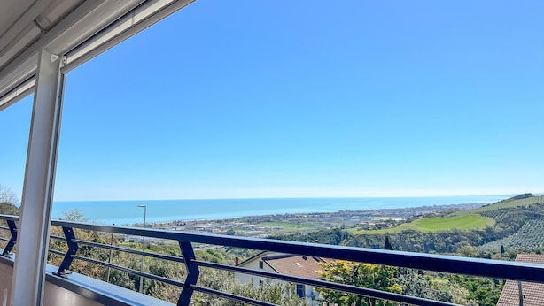 Un balcón con vistas despejadas al mar y colinas ondulantes.