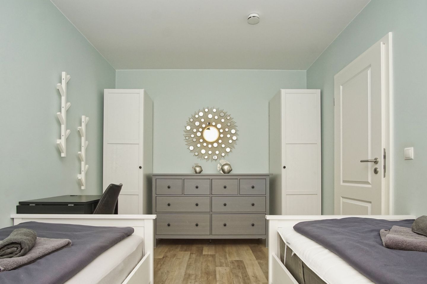 Een slaapkamer met twee bedden, een kaptafel, een spiegel en een plafondlamp.