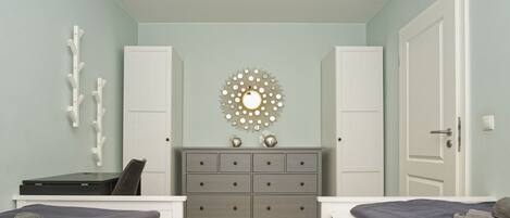 Een slaapkamer met twee bedden, een kaptafel, een spiegel en een plafondlamp.
